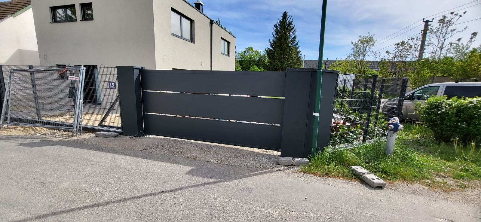 Prednji pogled na antracit kliznu kapiju sa uskim horizontalnim prorezima