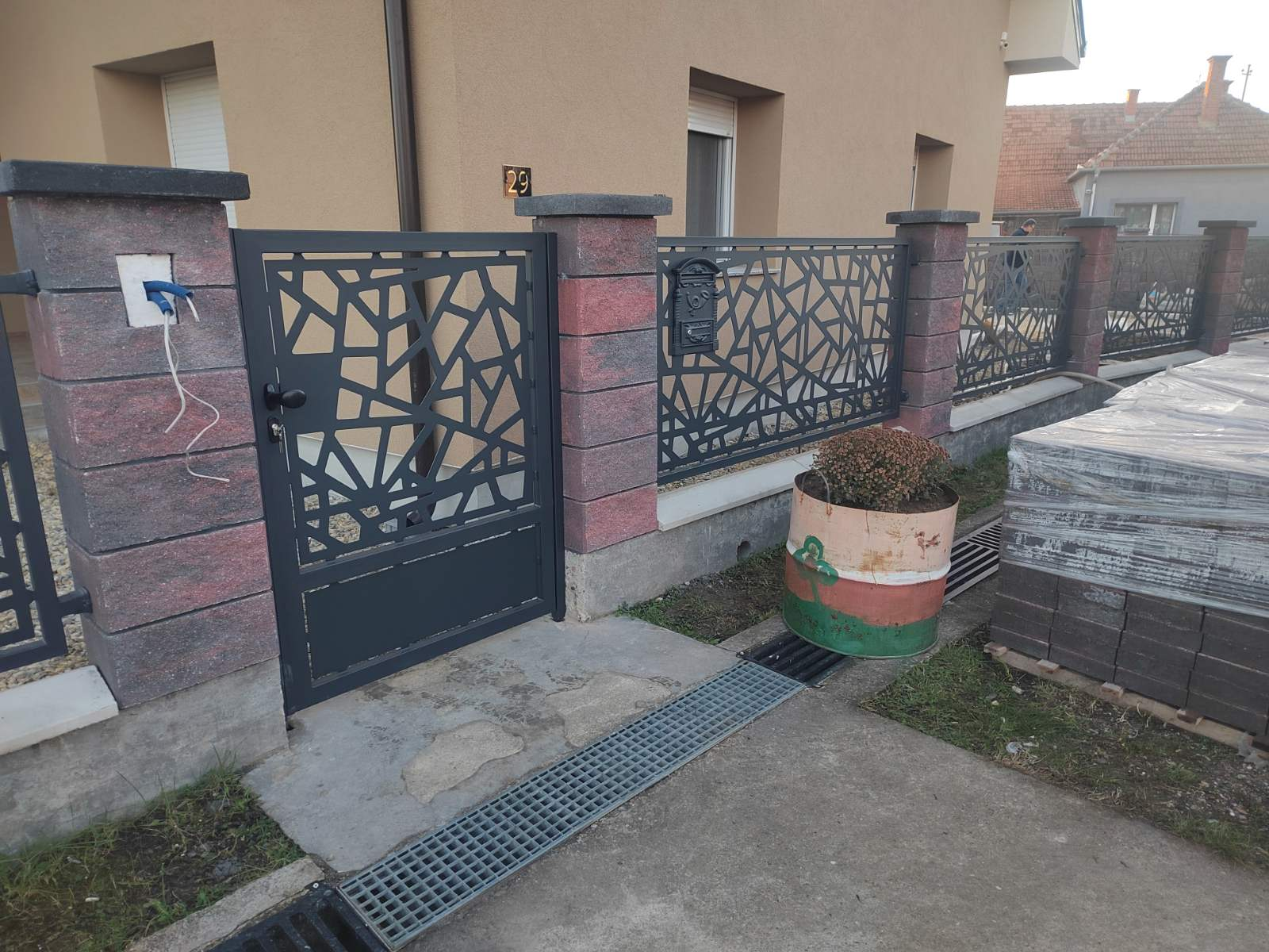Antracit pešačka kapija sa organskim sečenim motivom između kamenih stubova